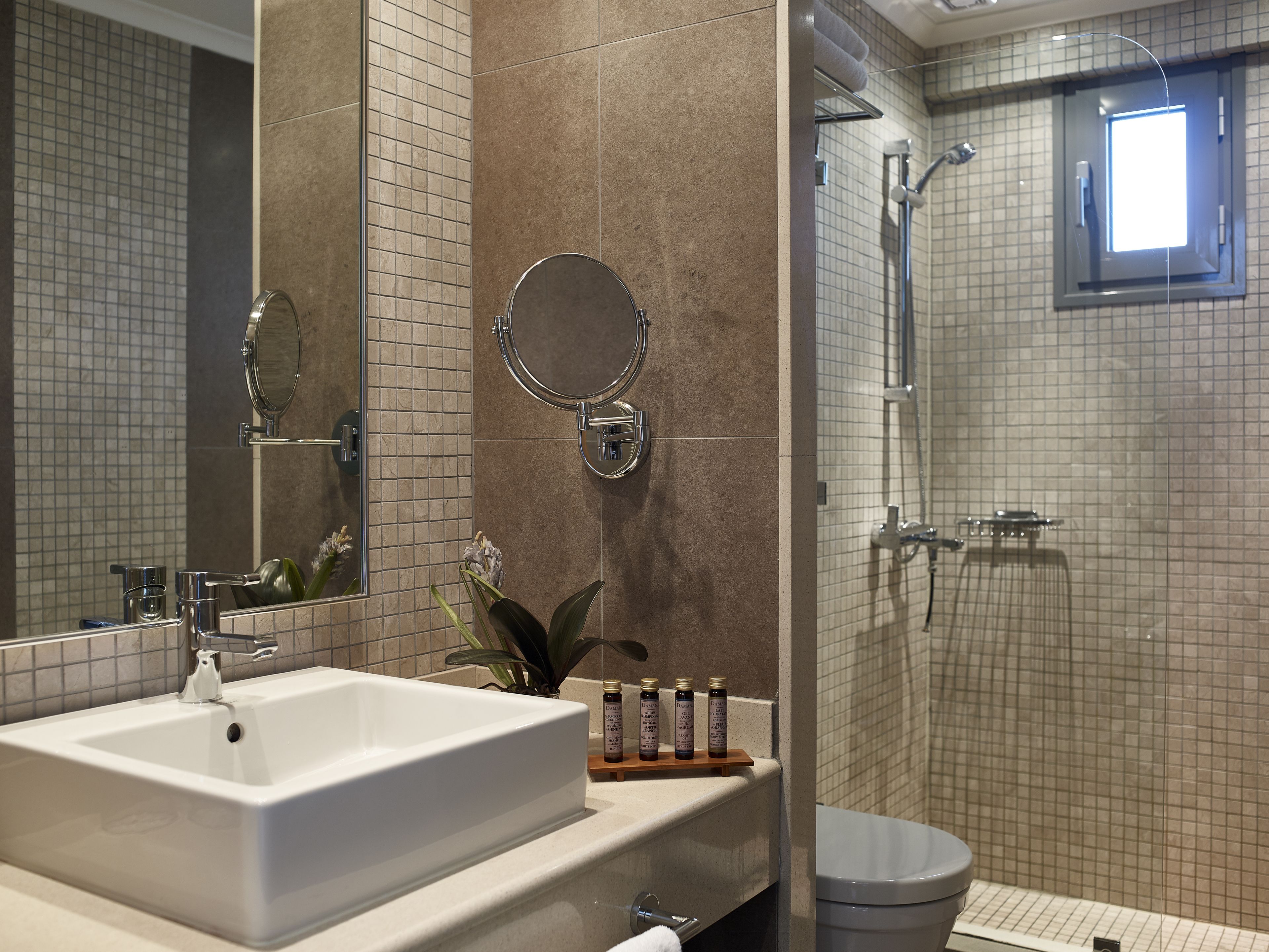 Une salle de bain moderne avec un grand miroir, un lavabo, des toilettes et un espace douche.