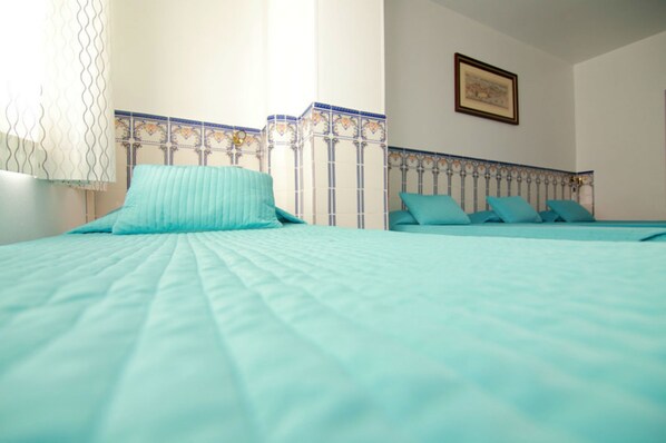 A bedroom with a bed, a window with curtains, and a decorative headboard.