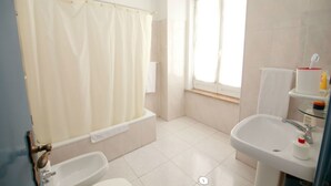 Ein Badezimmer mit einer Badewanne, einem Waschbecken und einem Fenster.