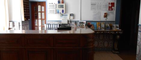 A reception area with a wooden desk, a computer, and a wall-mounted air conditioner.