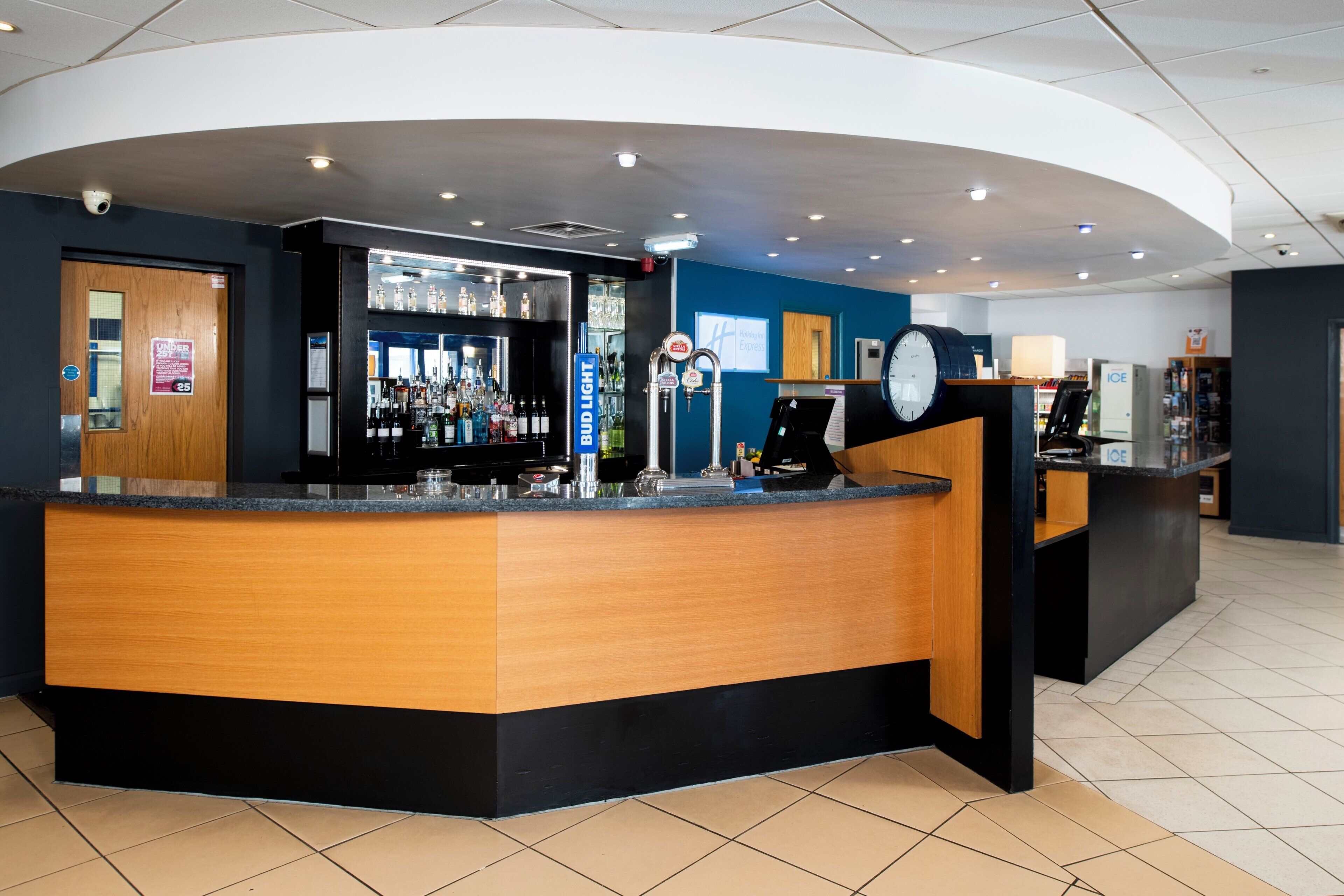 A bar area with a counter, shelves of bottles, and a clock.