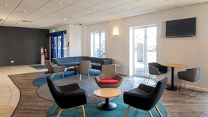 A modern lounge area with sofas, chairs, and a coffee table, featuring a large window and a flat-screen TV. - Holiday Inn Express Newcastle Gateshead by IHG (Newcastle-upon-Tyne)
