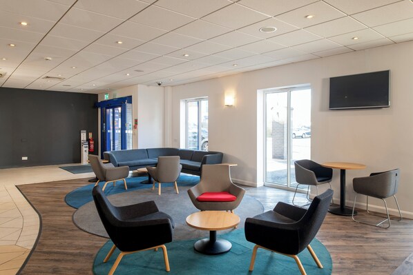 A modern lounge area with a sectional sofa, round tables, and comfortable chairs. - Holiday Inn Express Newcastle Gateshead by IHG (Newcastle-upon-Tyne)