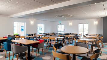A spacious indoor area with multiple tables and chairs arranged for dining or meetings.
