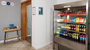 A vending machine stocked with snacks and beverages, a small table with a sign, and a door with a sign indicating the location of the stairs. - Holiday Inn Express Newcastle Gateshead by IHG (Newcastle-upon-Tyne)