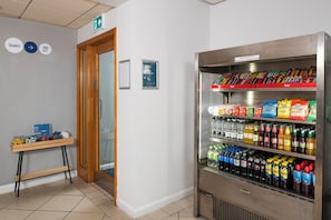 A vending machine stocked with snacks and beverages, a small table with a sign, and a door with a sign indicating the location of the stairs. - Holiday Inn Express Newcastle Gateshead by IHG (Newcastle-upon-Tyne)