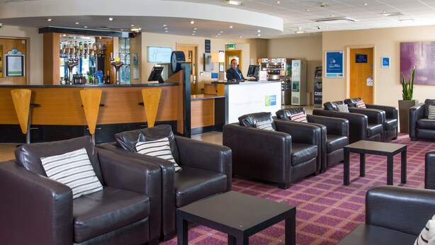 A hotel lobby with leather sofas, a reception desk, and a bar area. - Holiday Inn Express Newcastle Gateshead by IHG (Newcastle-upon-Tyne)