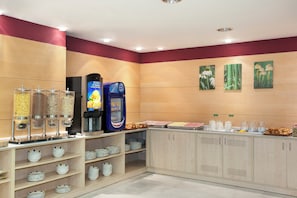 A breakfast area with a coffee machine, cereal dispensers, and a buffet with plates and milk pitchers. - Holiday Inn Express Madrid-Alcorcón by IHG (Alcorcon)