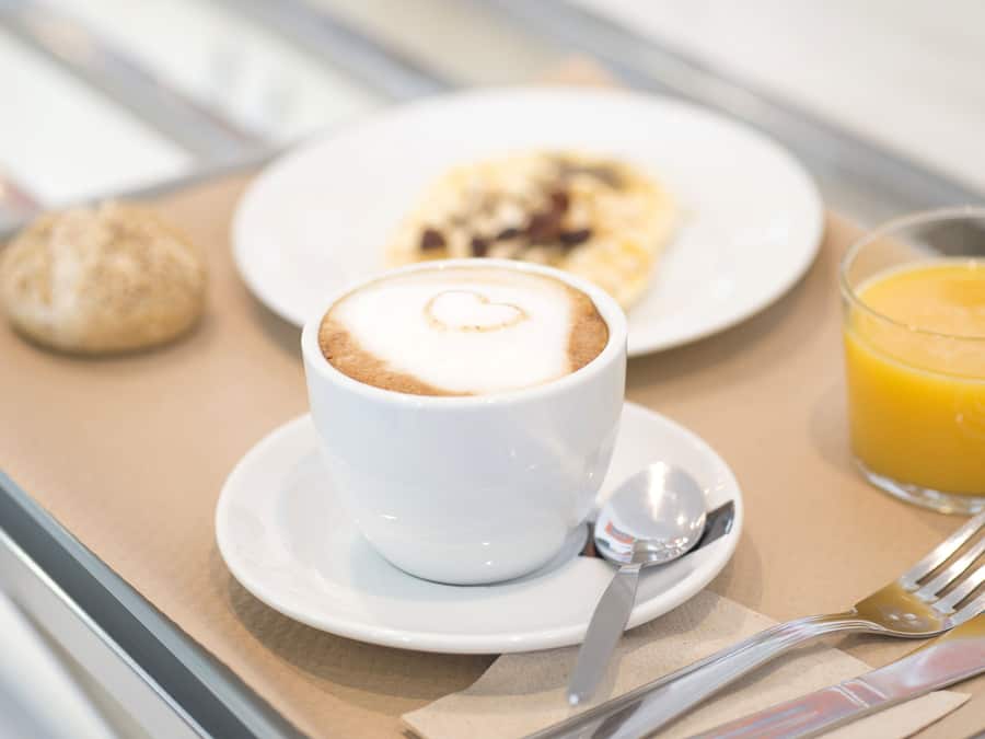 Una bandeja con una taza de café, un vaso de zumo de naranja, un pastel y un croissant.