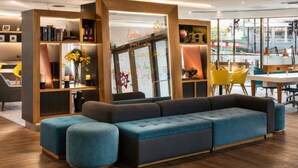 A modern interior with a sectional sofa, wooden bookshelves, and a view of the street.