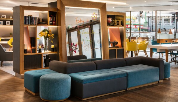 Een modern interieur met een hoekbank, houten boekenplanken en uitzicht op de straat.