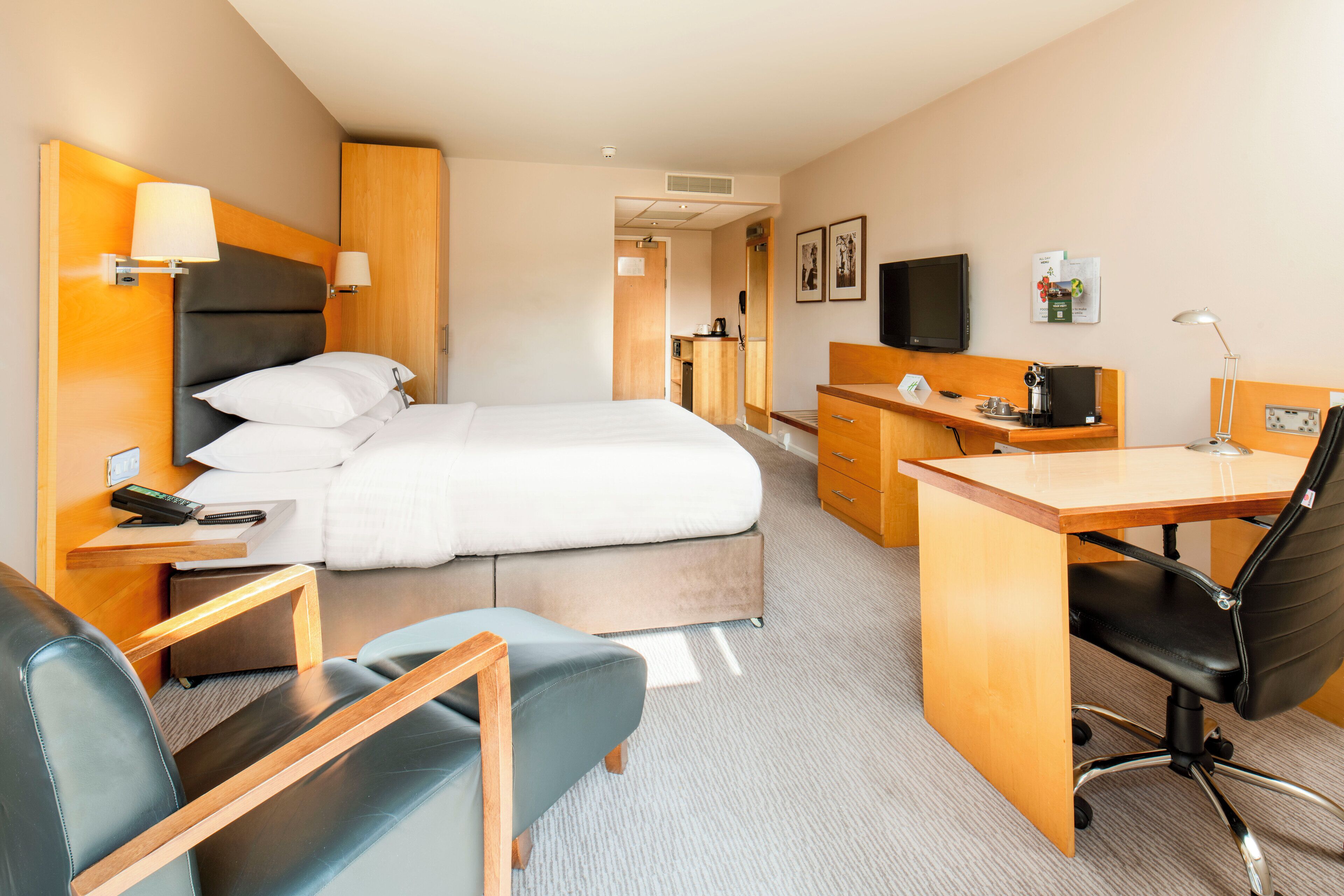 A hotel room with a bed, desk, chair, and a television.