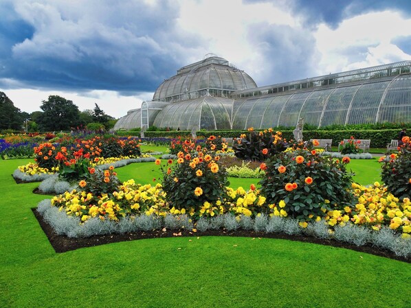 A greenhouse with a large glass structure, surrounded by well-maintained flower beds with various colors. - Holiday Inn London Brentford Lock by IHG (Brentford)