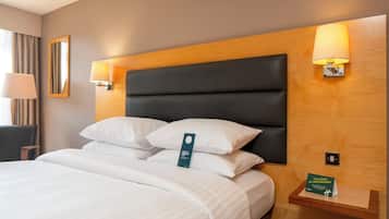 A neatly made bed with white linens, a dark headboard, and two wall-mounted lamps.