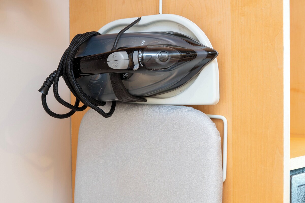 An iron on a white ironing board in a room with wooden paneling.