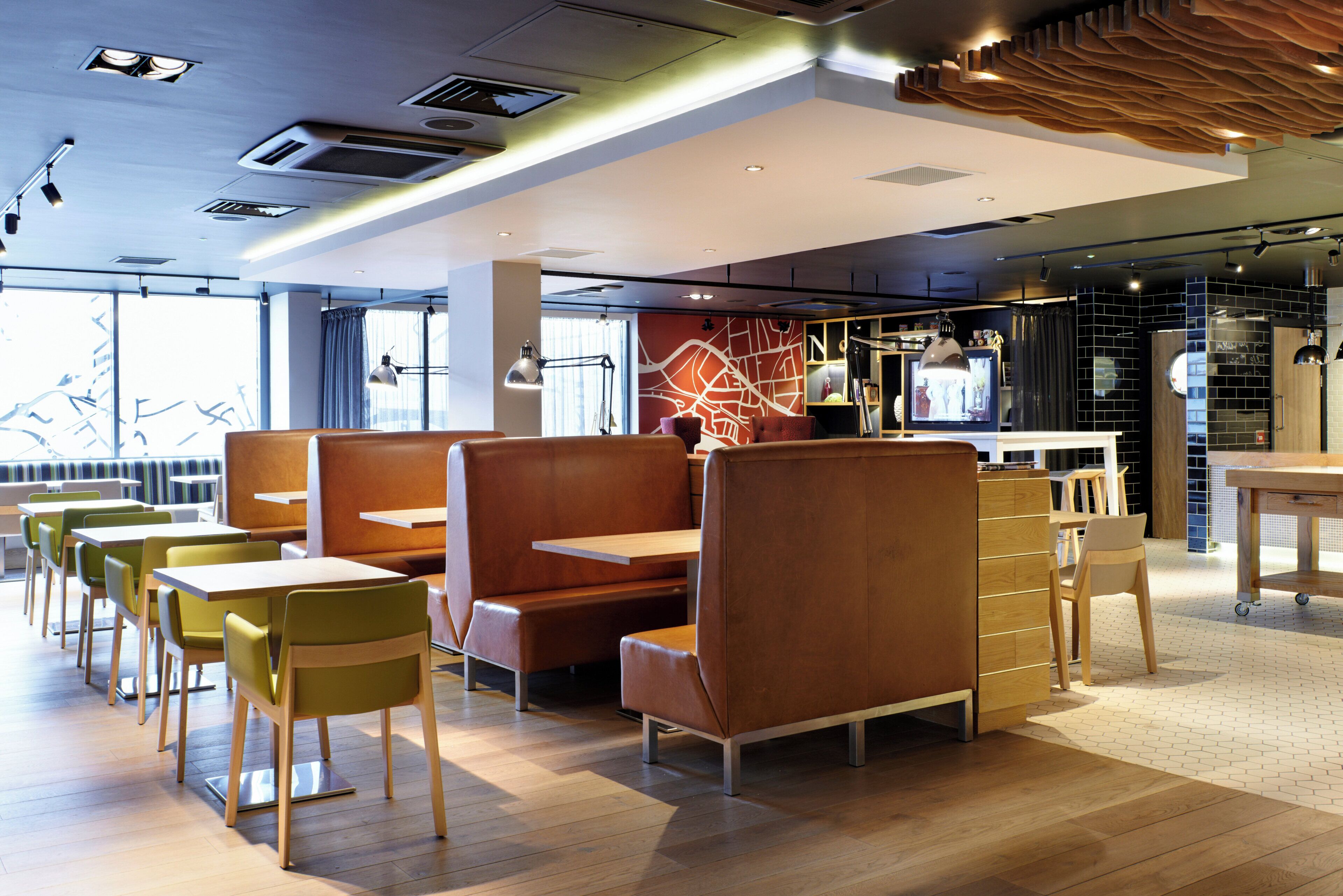 A modern restaurant interior with booths, tables, and a bar area.