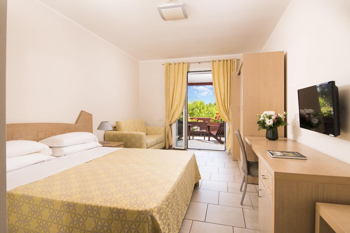 Ein Hotelzimmer mit Bett, Schreibtisch, Fernseher und Blick ins Freie.