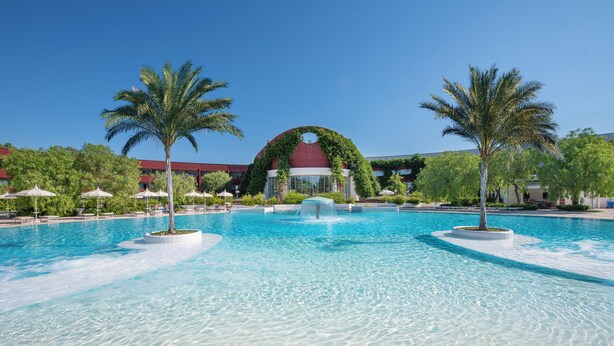 A large pool with palm trees, a fountain, and a building with a dome. - Ethra Reserve - Calanè 4* (Castellaneta)