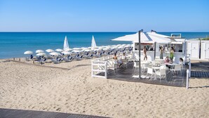 A beachside restaurant with outdoor seating, white umbrellas, and a view of the ocean. - Ethra Reserve - Calanè 4* (Castellaneta)