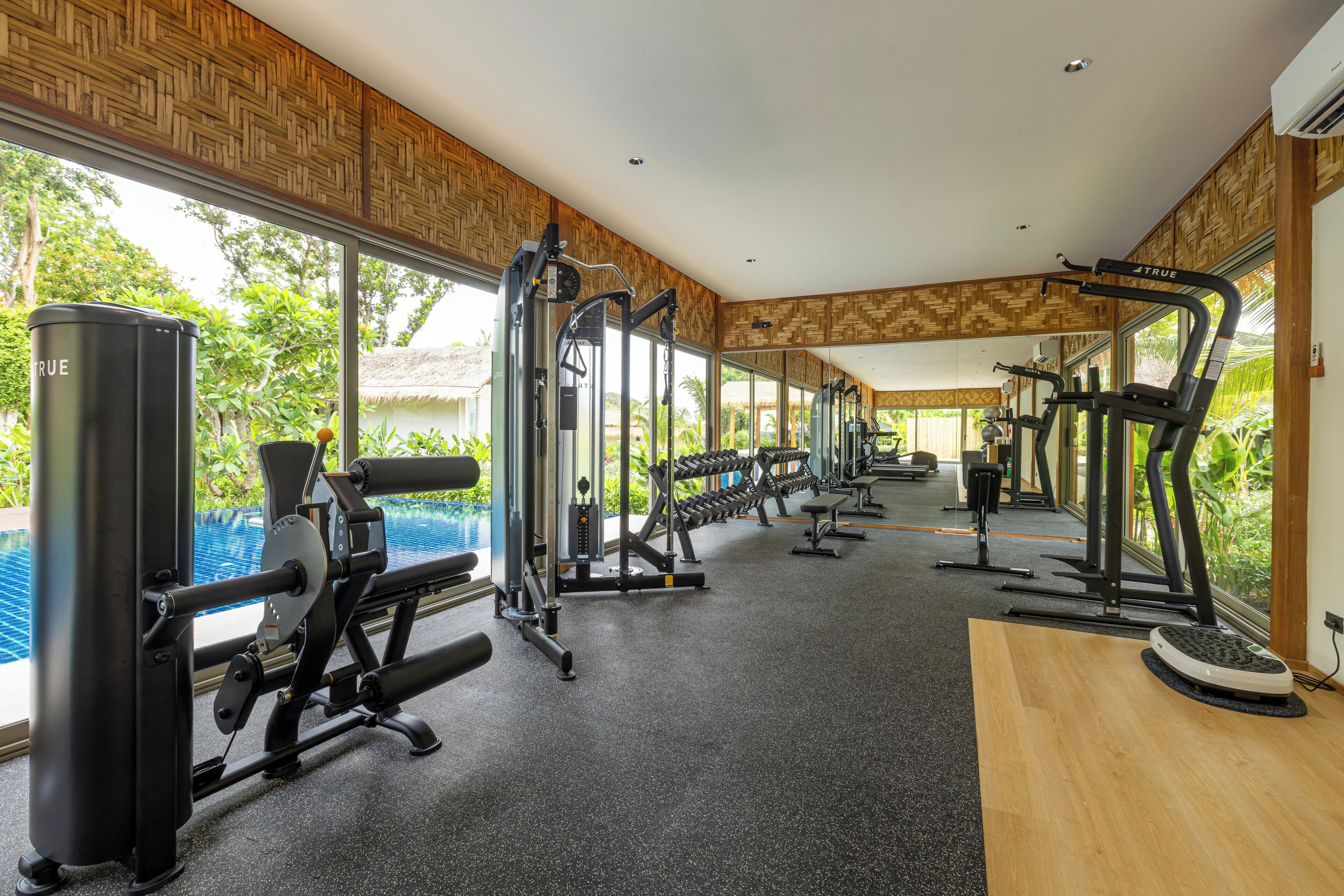 A gym with various exercise equipment, large windows, and a view of the outdoors.