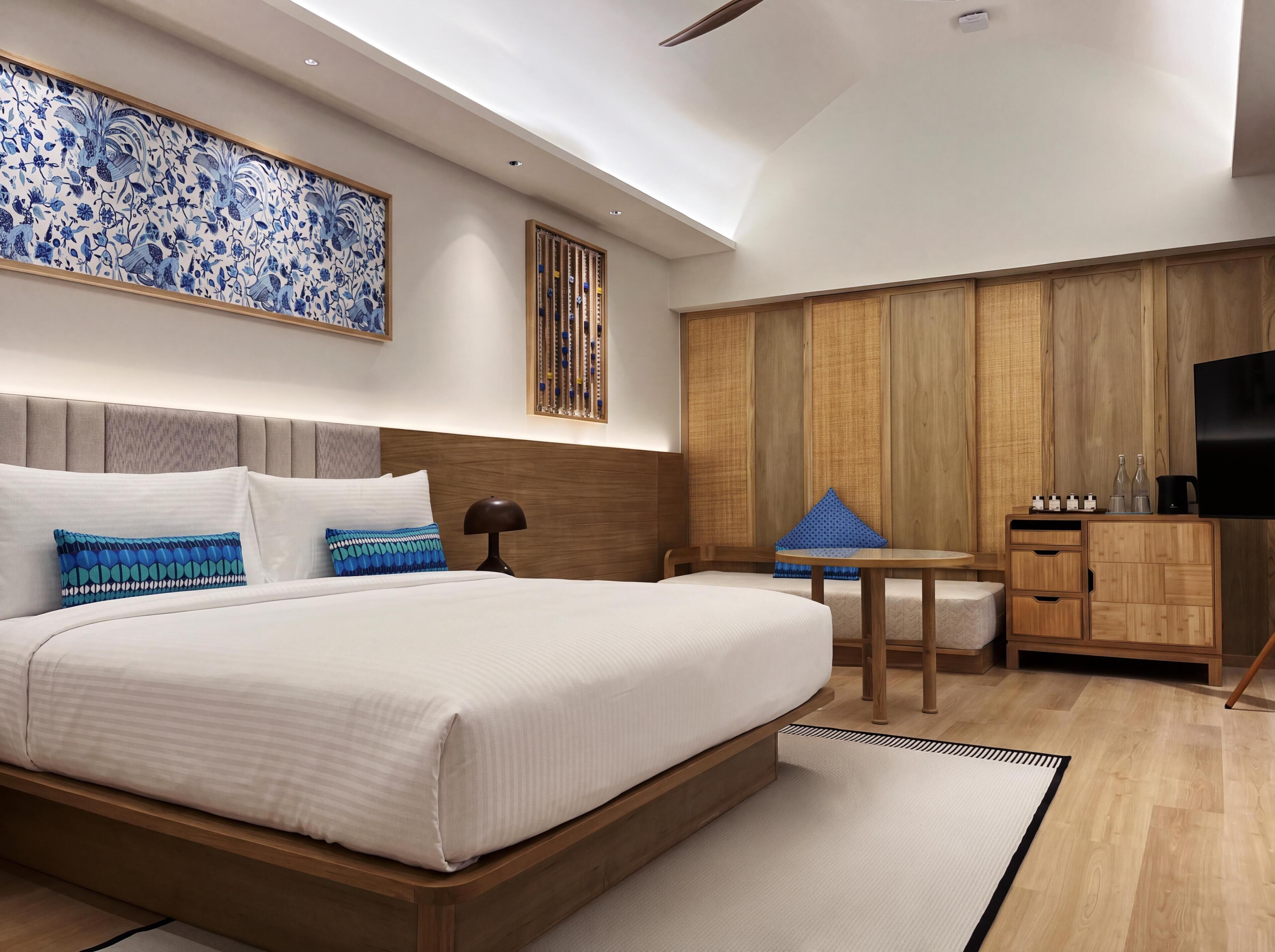 Une chambre moderne avec un grand lit, des tables de chevet, une télévision et une armoire en bois.