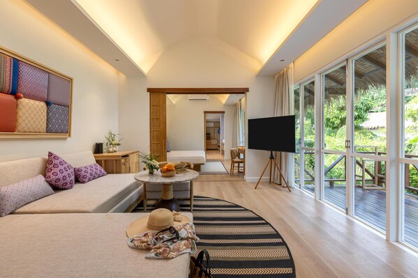 A modern room with a sofa, a dining table, a TV, and large windows.