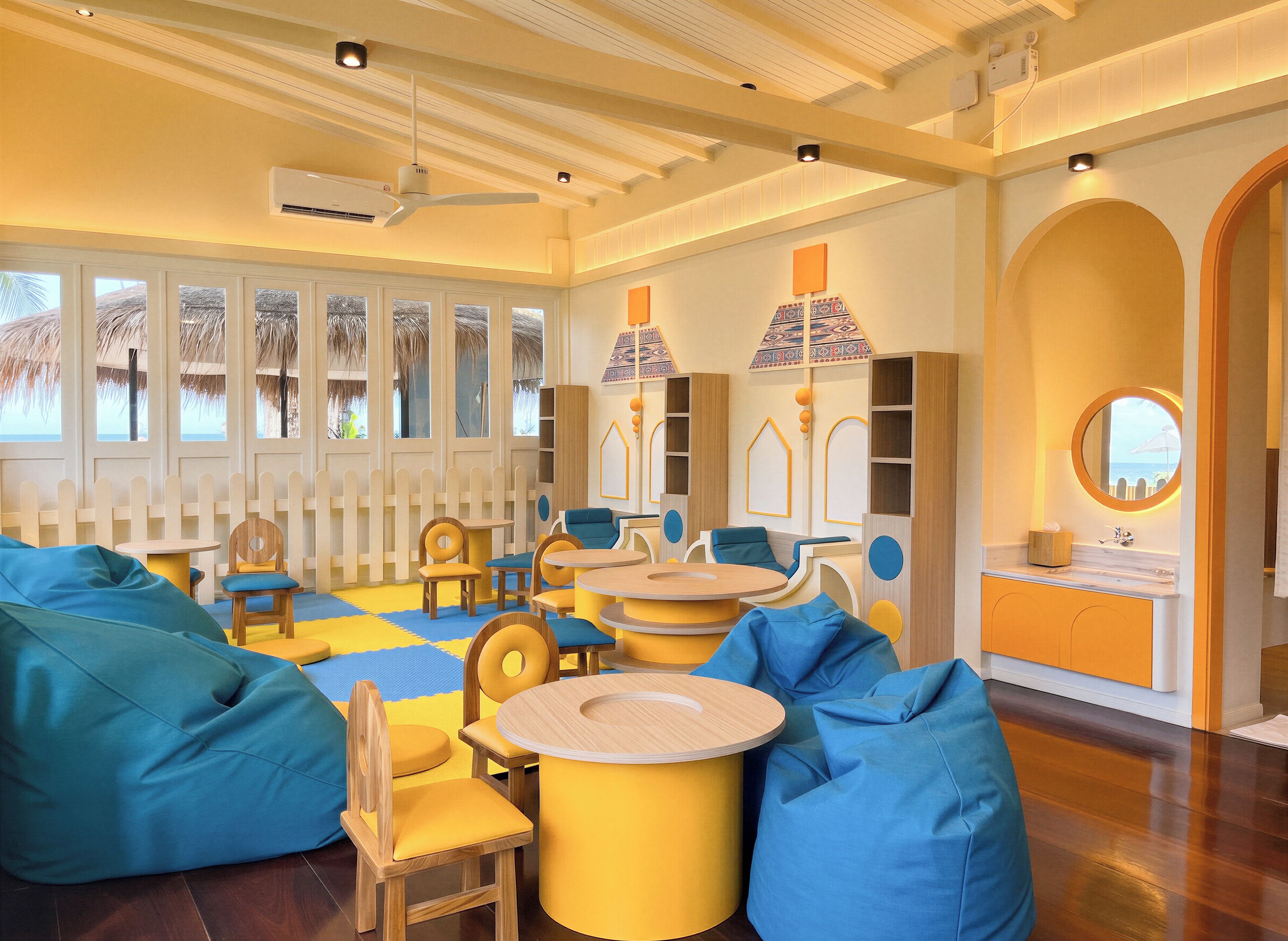 A room with a wooden floor, a round table, chairs, a sofa, and a large window with a view.