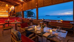 Un restaurante con vistas al mar, paredes de madera y mesas dispuestas para comer.