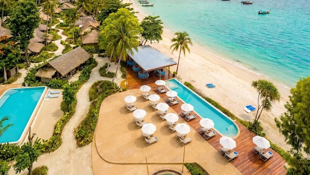 Un resort con piscina, zona de descanso y acceso a la playa.