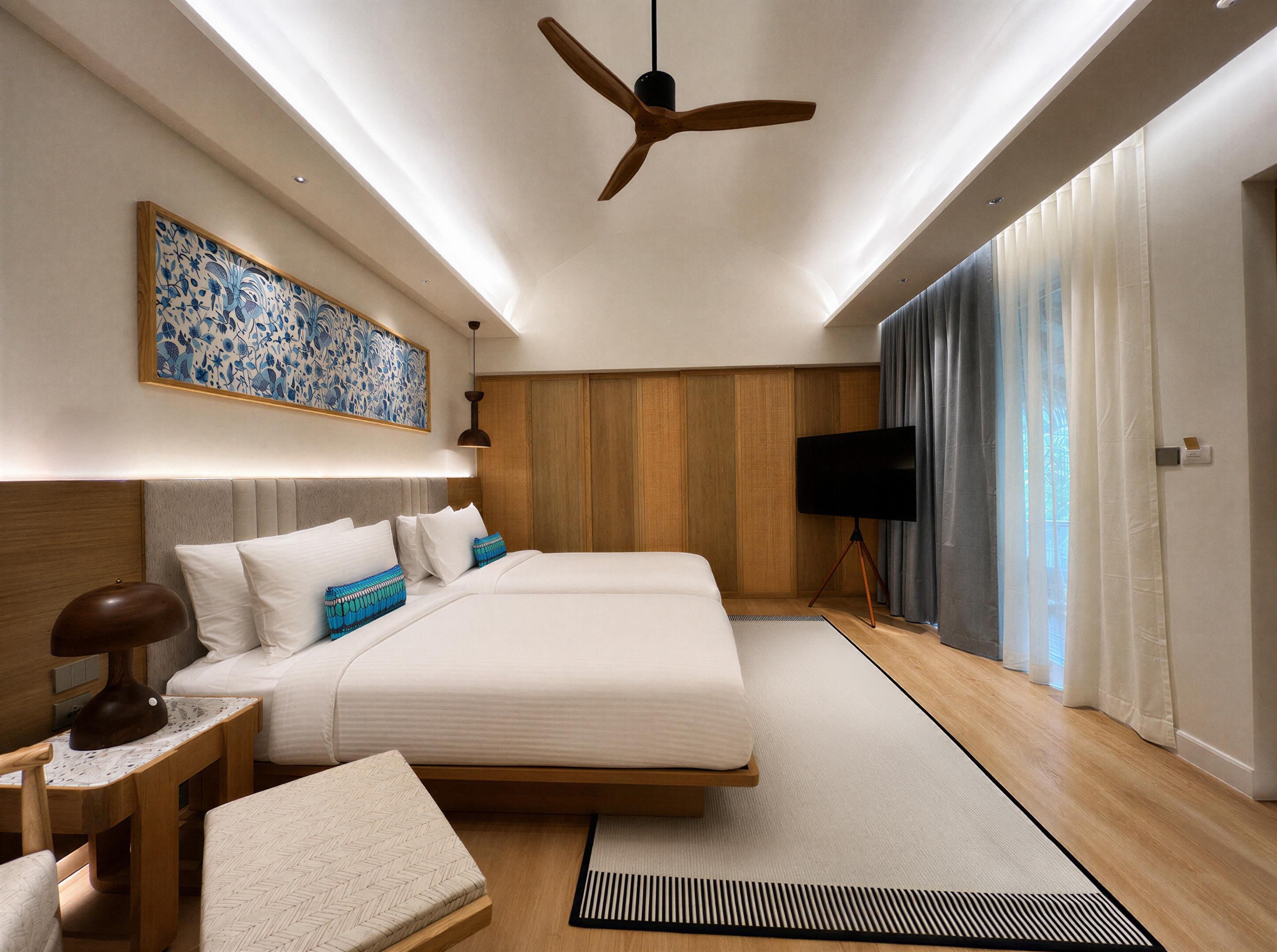 Une chambre d’hôtel moderne dotée d’un grand lit, d’un téléviseur à écran plat et d’un ventilateur de plafond.