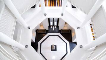 A modern hotel lobby with a geometric floor design, white walls, and a central statue.