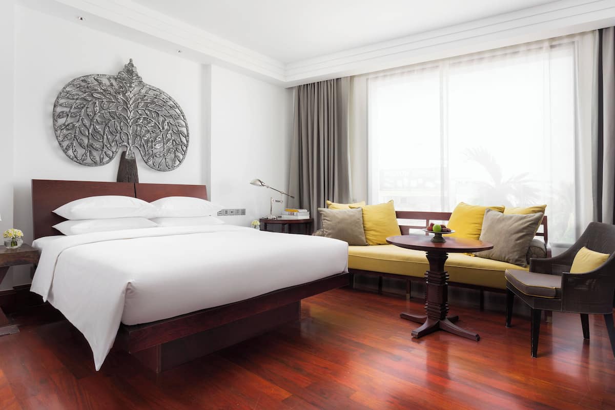 Een hotelkamer met een groot bed, een bank, een kleine tafel en een decoratief wandobject.