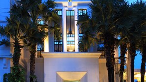 Un hôtel moderne doté d’une entrée imposante, de grandes fenêtres et de palmiers.
