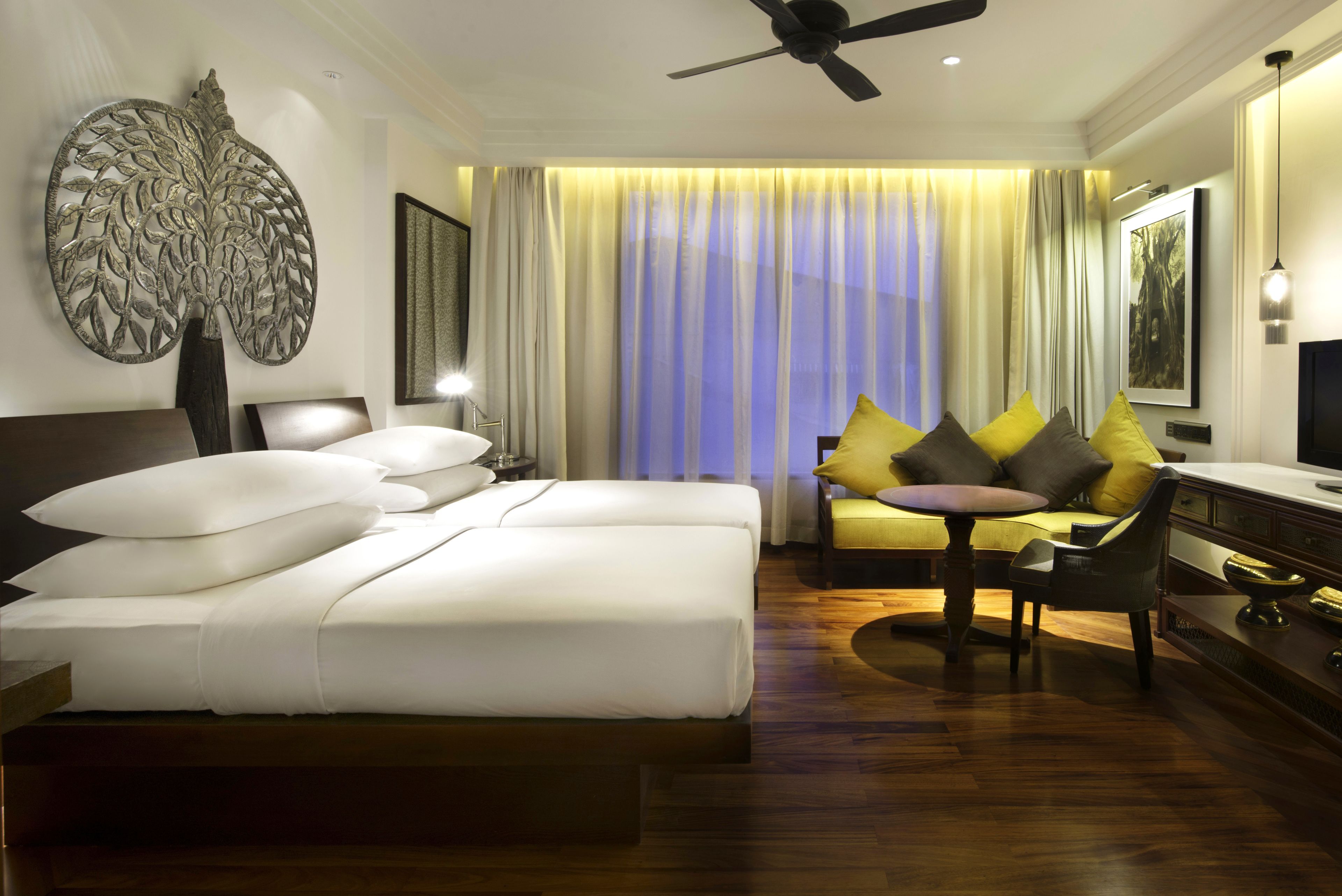 Habitación de hotel con una cama grande, un sofá, un escritorio y un ventilador de techo.
