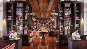 Un hall d’hôtel avec un comptoir d’accueil central, deux réceptionnistes et une fontaine décorative.