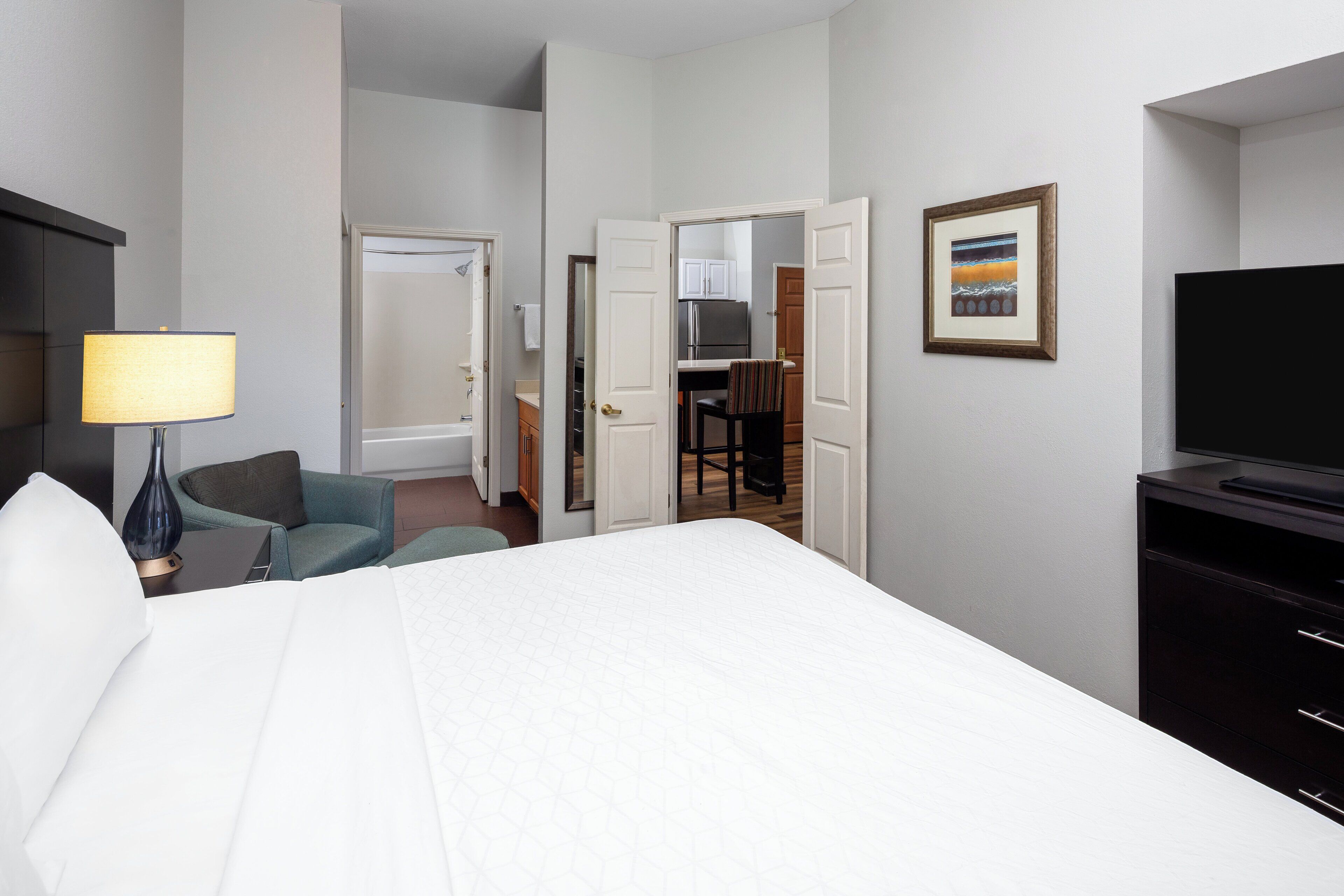 Een hotelkamer met een bed, een bureau, een stoel, een televisie en een schilderij aan de muur.