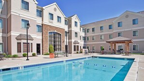 A hotel with a swimming pool, outdoor seating, and a covered patio area. - Staybridge Suites O'Fallon Chesterfield by IHG (O'Fallon)