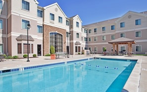 A hotel with a swimming pool, outdoor seating, and a covered patio area. - Staybridge Suites O'Fallon Chesterfield by IHG (O'Fallon)