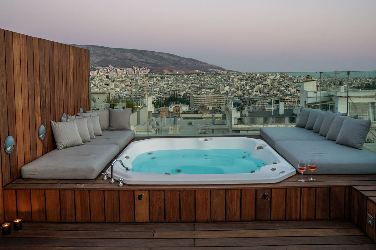 A rooftop terrace with a hot tub, seating area, and a city view.