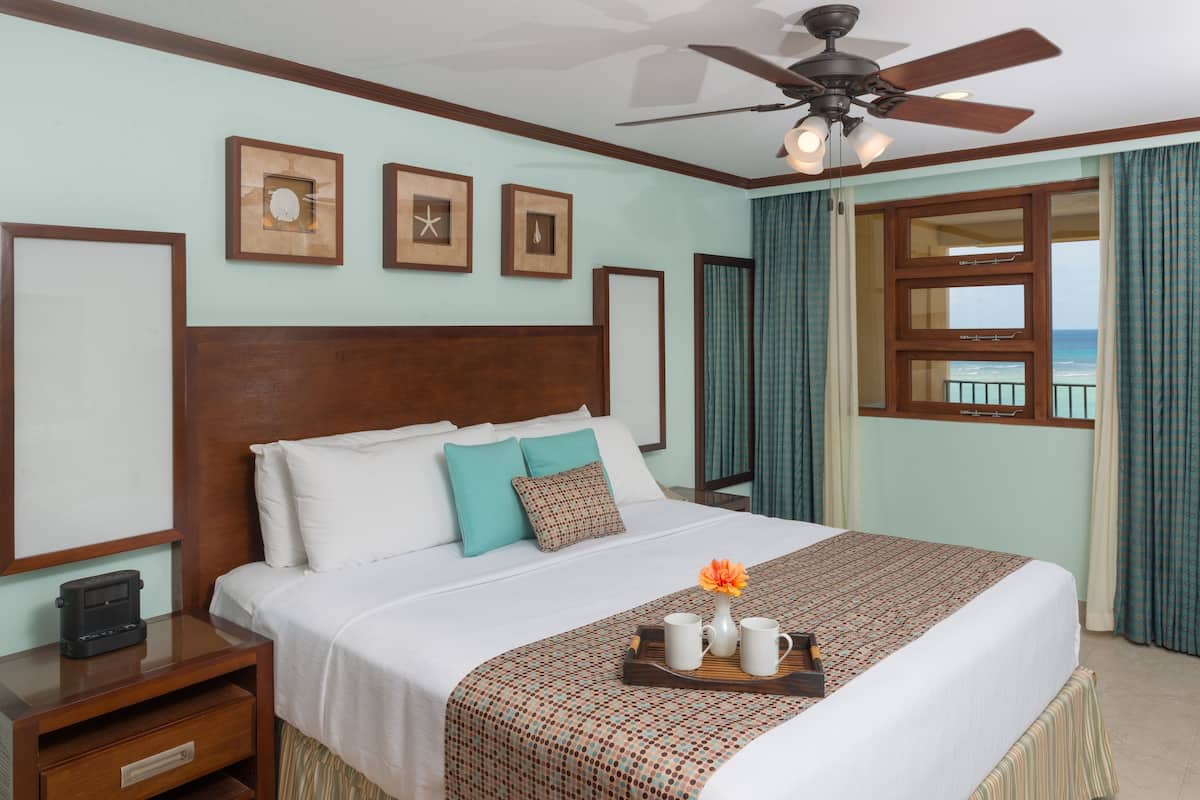 A neatly made bed with a patterned bedspread, a bedside table with a radio, and framed pictures on the wall.