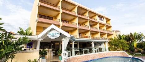 Un hotel con piscina, asientos al aire libre y un cartel que dice 'On the Bay Eat, Drink, Bajan'.