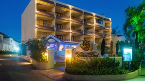 Un hotel con varios balcones, un letrero que dice 'Yellow Bird Hotel' y una entrada bien iluminada.
