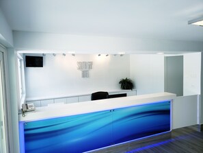 A modern reception area with a white counter, a mounted TV, and a sign that reads "SOUTH GAP TITLE".