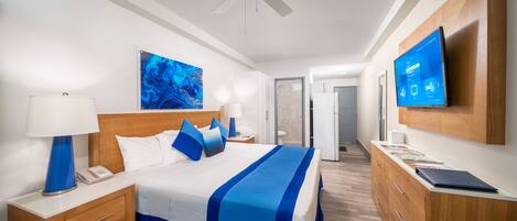 A hotel room with a bed, nightstand, lamp, and a flat-screen TV on the wall.
