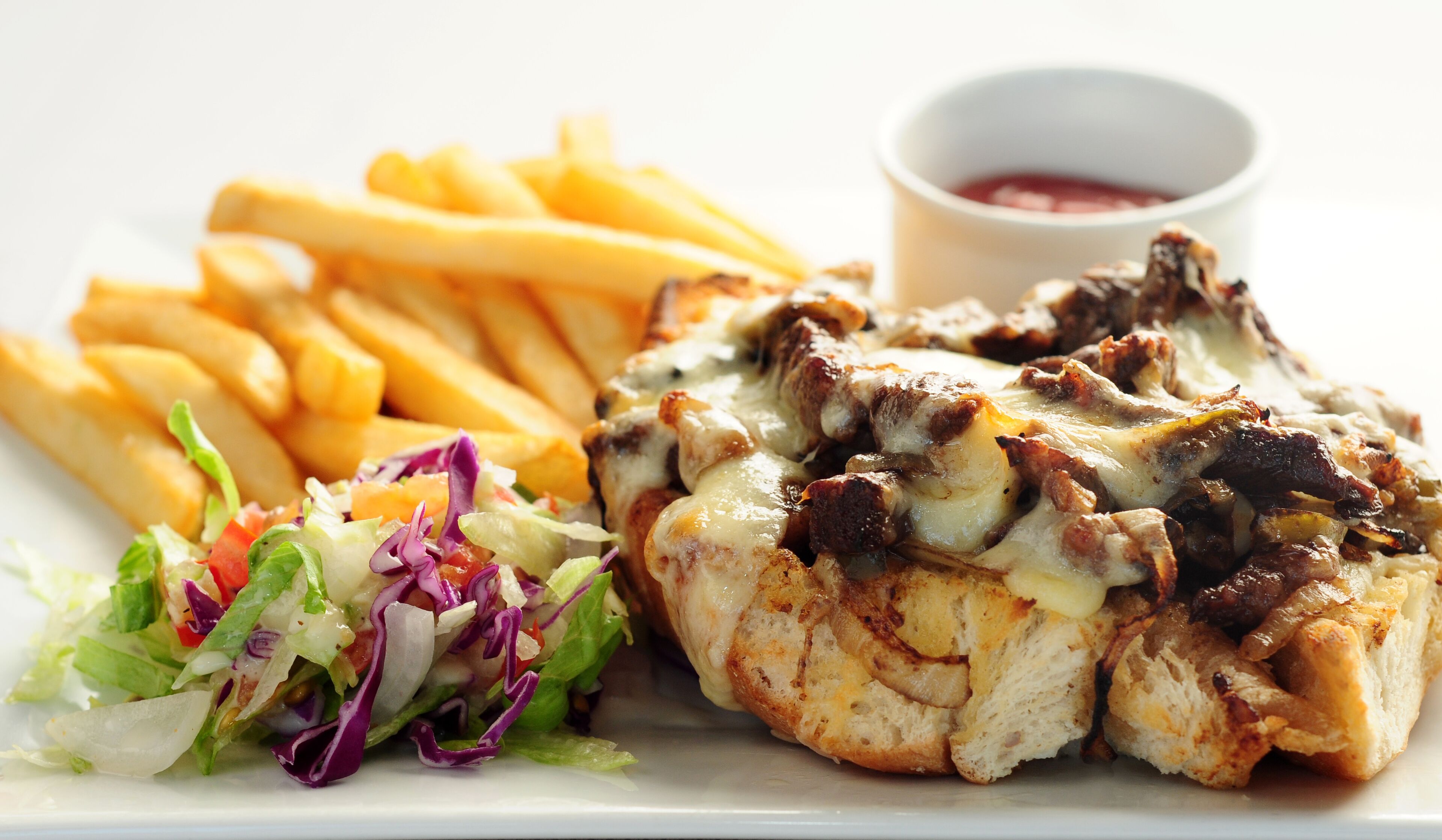 Um prato com frango grelhado, batatas fritas e uma salada.