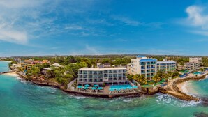 Un resort con zona de piscina, varias construcciones y una playa.
