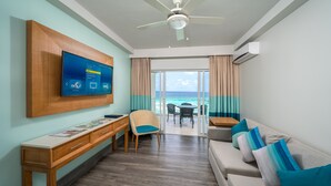 Una habitación de hotel moderna con un escritorio de madera, un sofá cómodo, un ventilador de techo y un televisor montado en la pared.