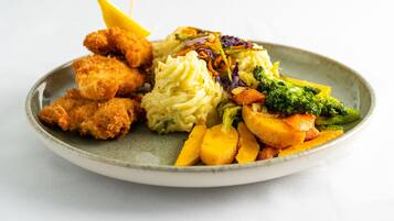 A plate with breaded chicken, mashed potatoes, and mixed vegetables.