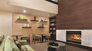 A modern living room with a green sofa, a round coffee table, and a fireplace. - Country Inn & Suites by Radisson, Gainesville, FL (Gainesville)