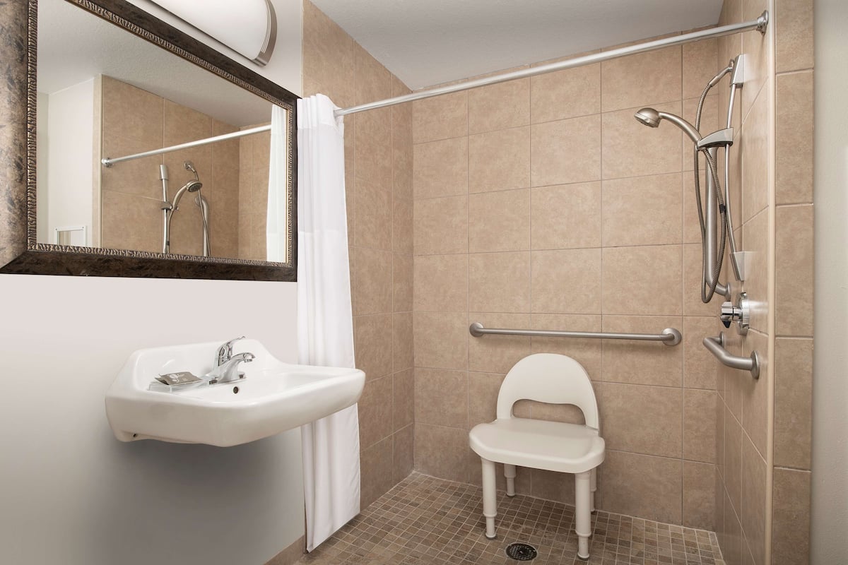 A bathroom with a sink, mirror, shower, and toilet.